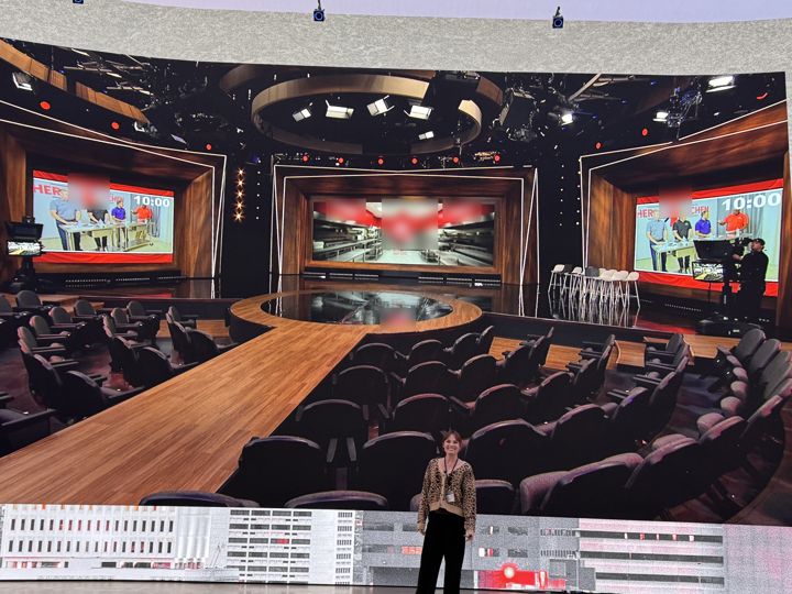 Event stage with a large wraparound screen showing a studio set